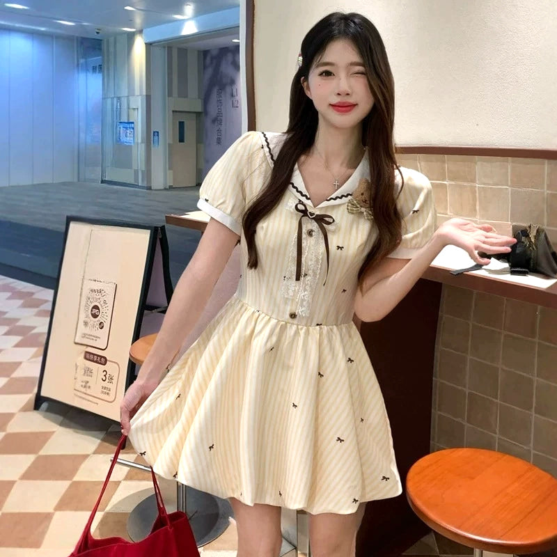 大きいサイズ レディース 大きいサイズ レディースのクリームイエロー半袖ミニワンピース。ストライプと小リボン柄、セーラー襟とブラウンリボン、ふんわり裾のガーリーデザイン着用例