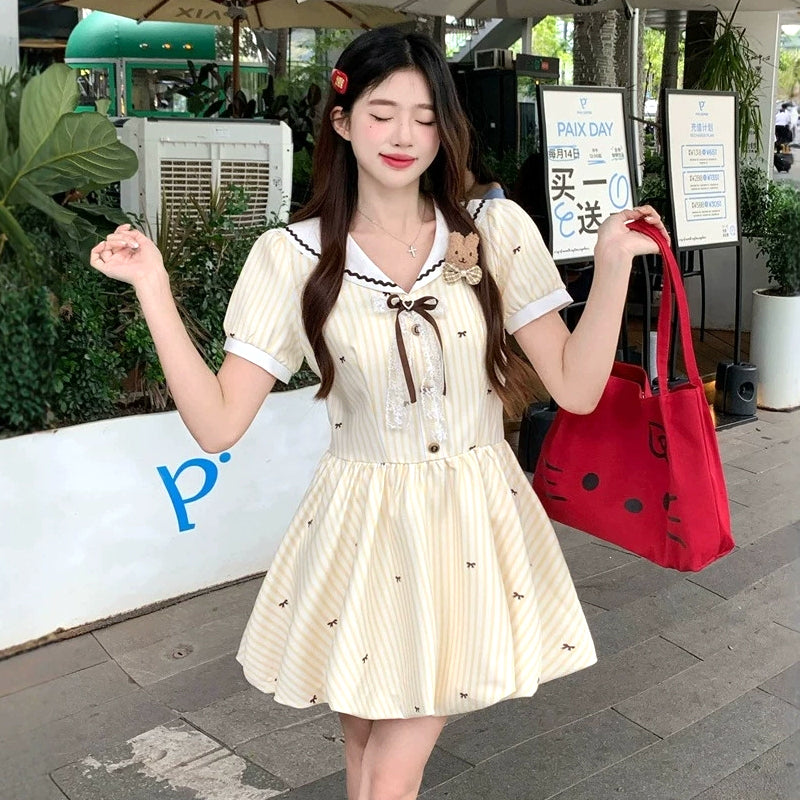 大きいサイズ レディース 大きいサイズ レディースのクリームイエロー半袖ミニワンピース。ストライプと小リボン柄、セーラー襟とブラウンリボン、ふんわり裾のガーリーデザイン着用例